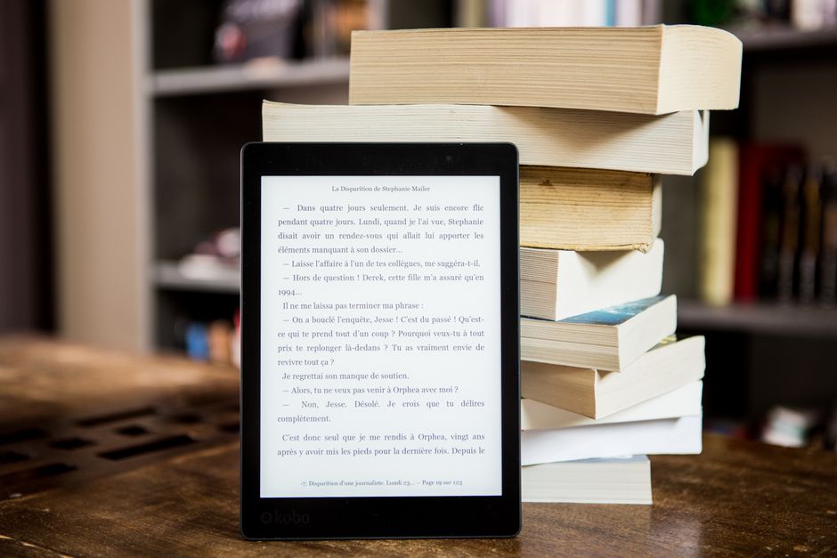 A close-up view of various colorful books lined up on a rustic wooden shelf indoors.