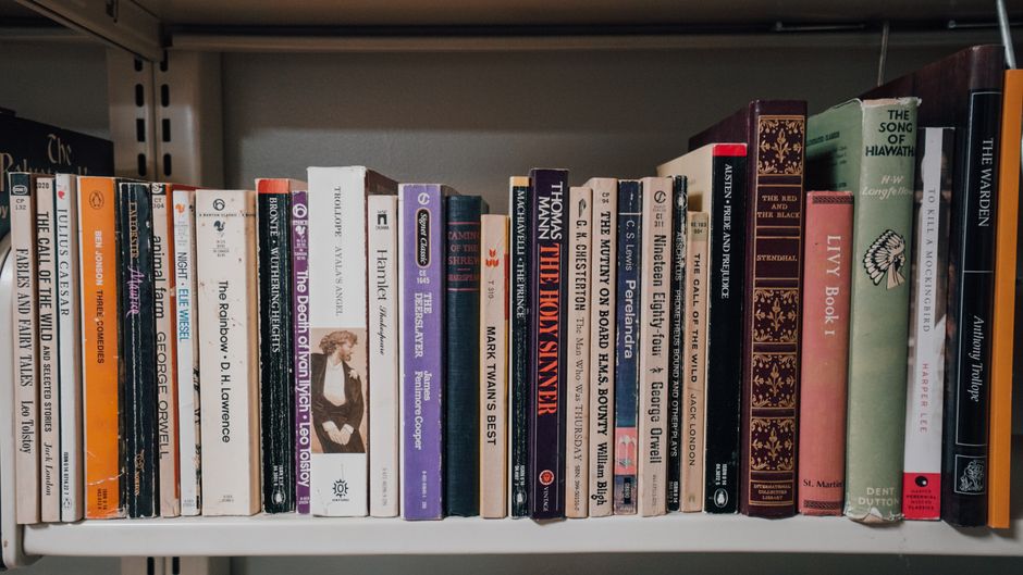 Close-up of a stack of vintage books with worn bindings, showcasing aged paper and textures.