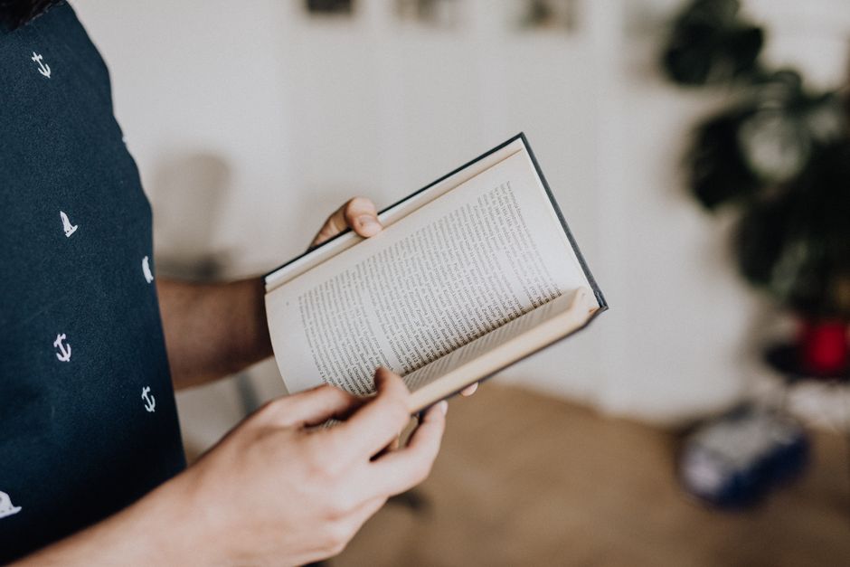 A warm cup of latte with beautiful latte art, next to an open book on a rustic table.